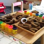 alphabet blocks and play dough sitting on a kindergarten students desk in a classroom