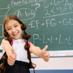 Young girl giving thumbs up in front of chalkboard with equations on it