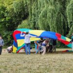 Students play with a multi-colored parachute.