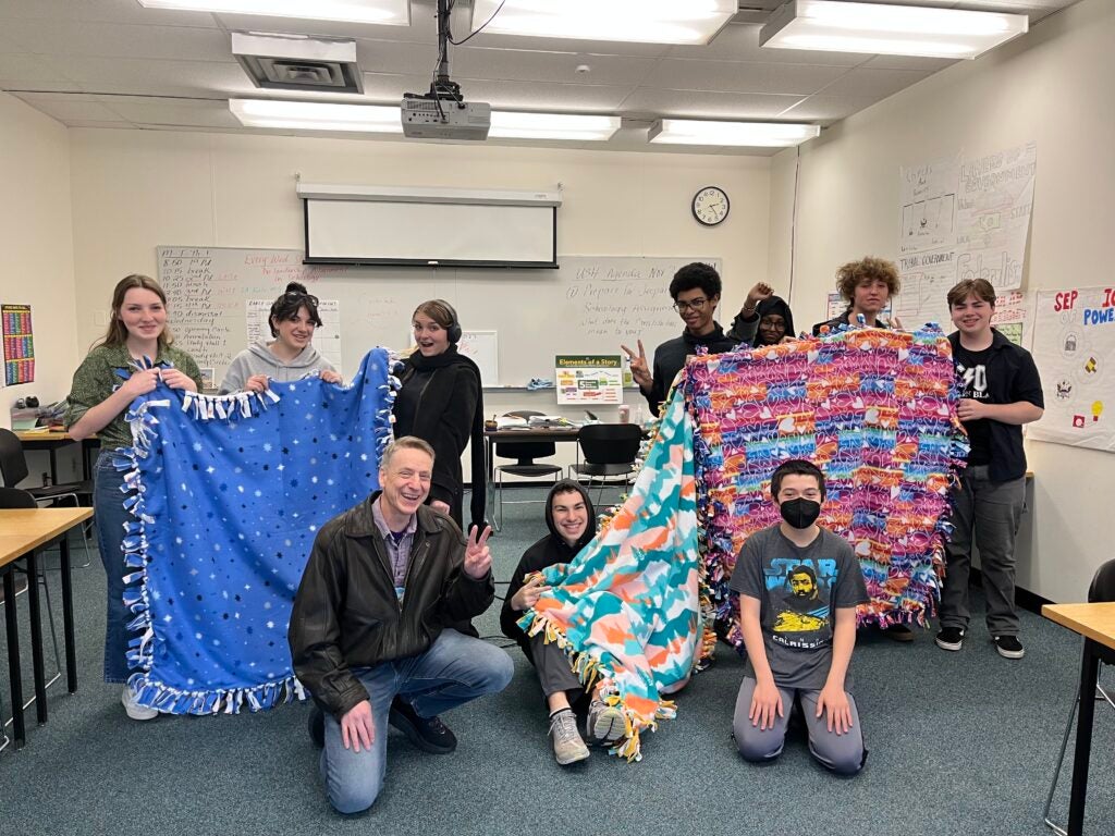 Students and staff holding up tie blankets. 