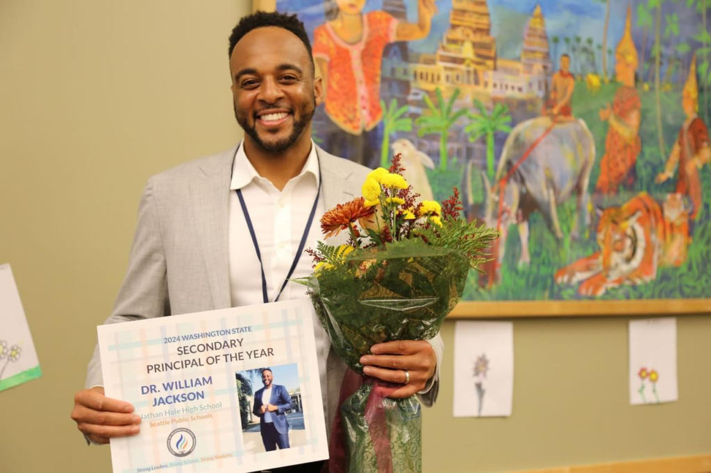 Dr. William Jackson holding his 2024 Secondary Principal of the Year award and flowers.