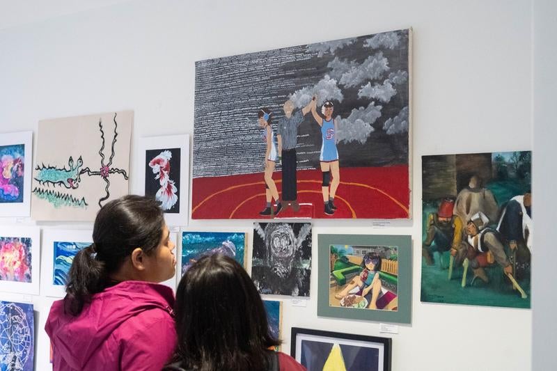 Adult and student looking at wall of artwork.