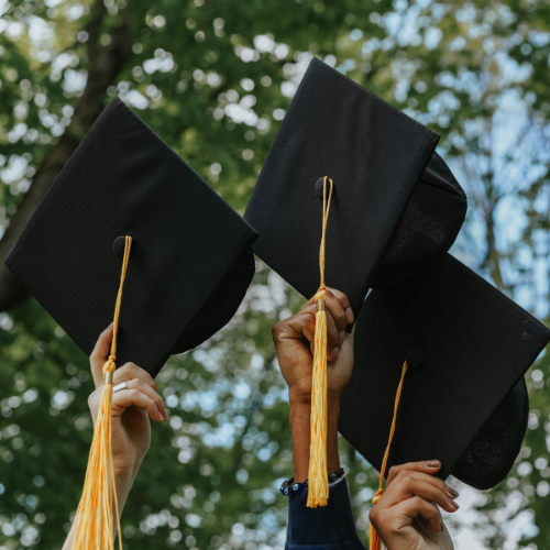 three hands holding graduation caps