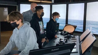 Three students and an adult on a boat deck