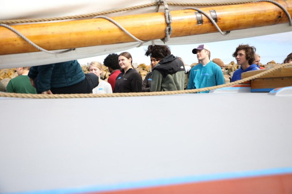 Students aboard historic schooner under mast. 