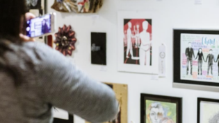 Person talking a photo of artwork on the wall. Photo from the Seattle Art Museum promotion of the event.