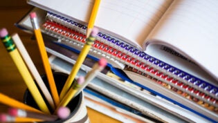 Jar of pencils and stack of notebooks