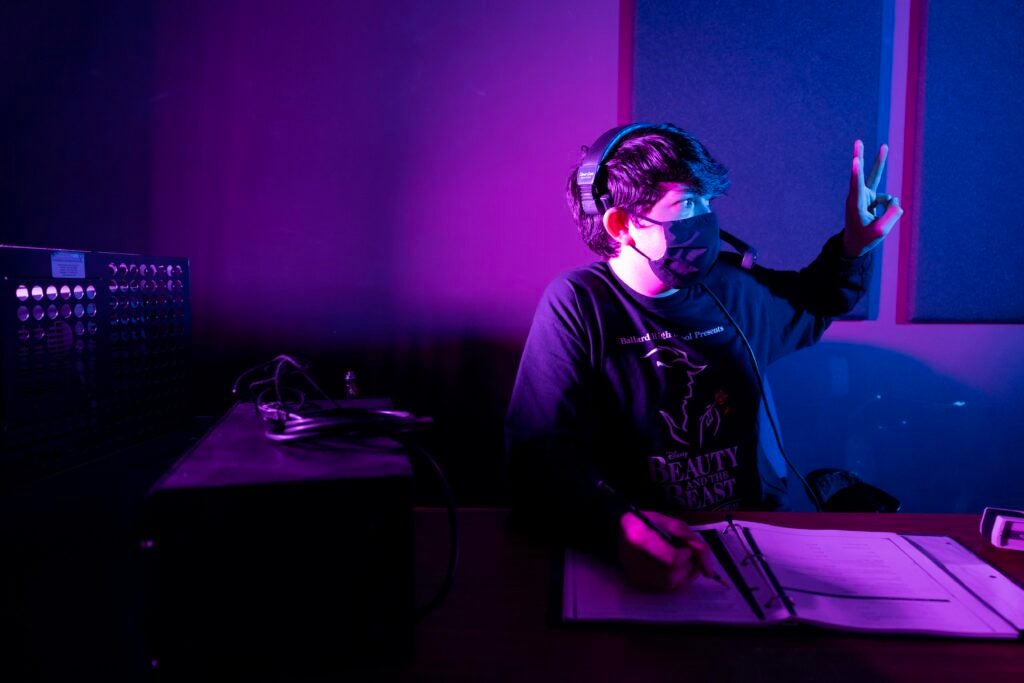 Student with mask sitting at electronic booth