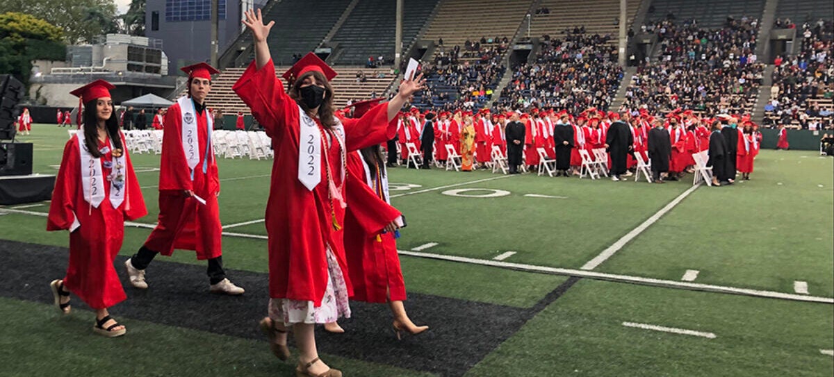 Students in red cap and gown at Memorial Stadium