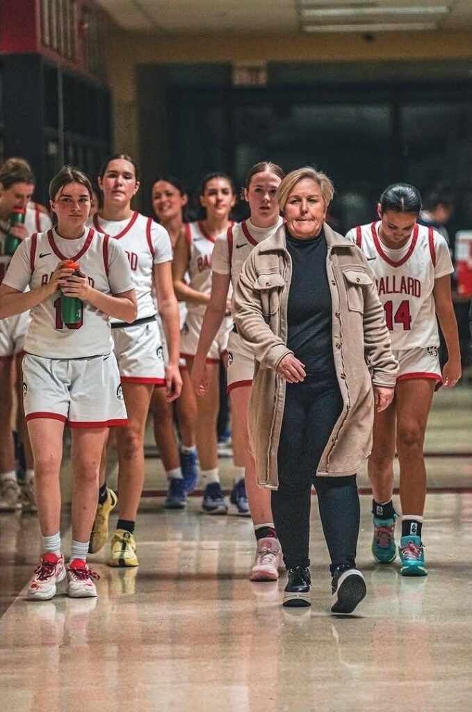 Girls Basketball players walking on the court with Coach Jennifer Anderson