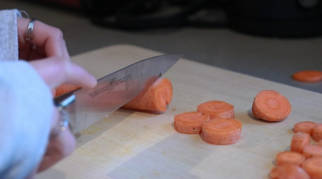Cutting board with hand and knife cutting carrots. Chop Chop Film