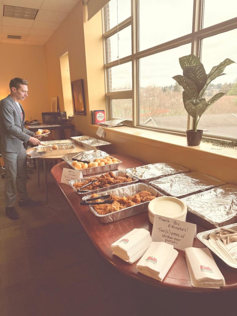 Staff at table filled with food for staff appreciation.