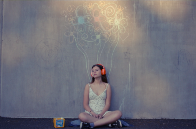 Person sitting at wall with flower mural.