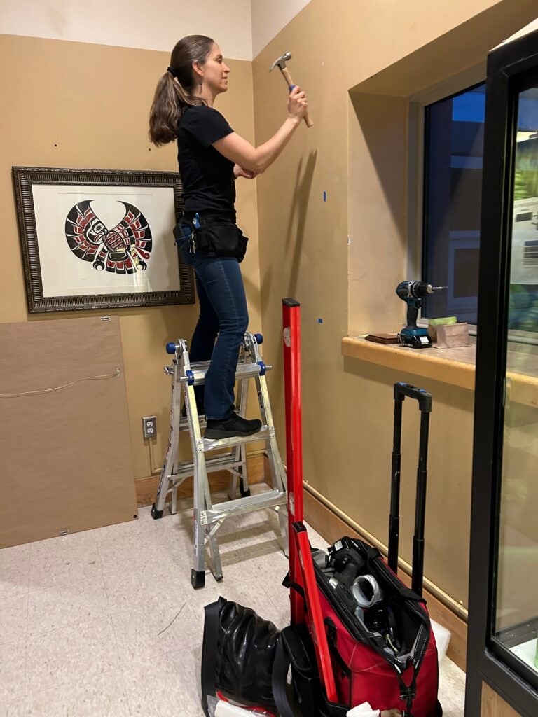 Volunteer hanging paintings on the wall at the Ballard HS.